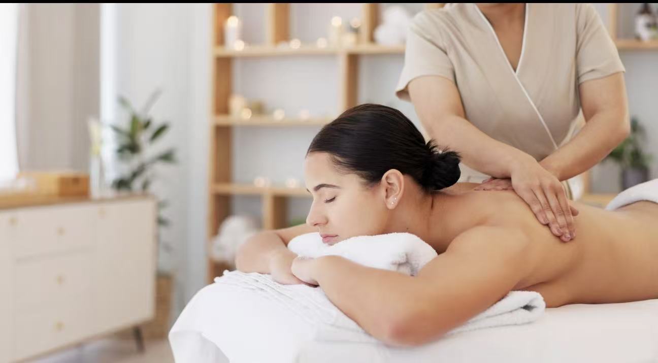 A guest receiving a calming back and shoulder massage from a senior therapist in a warm, candlelit treatment room at TAO Therapeutic Massage Spa in Vienna, VA